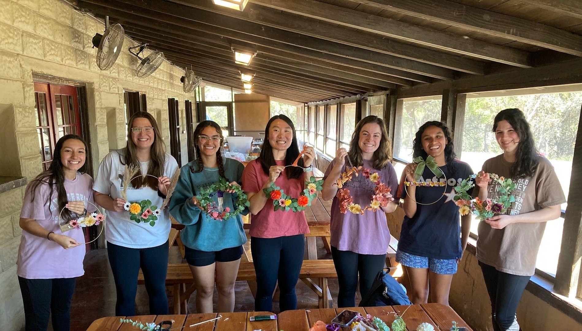 Women holding custom made wreaths and smiling